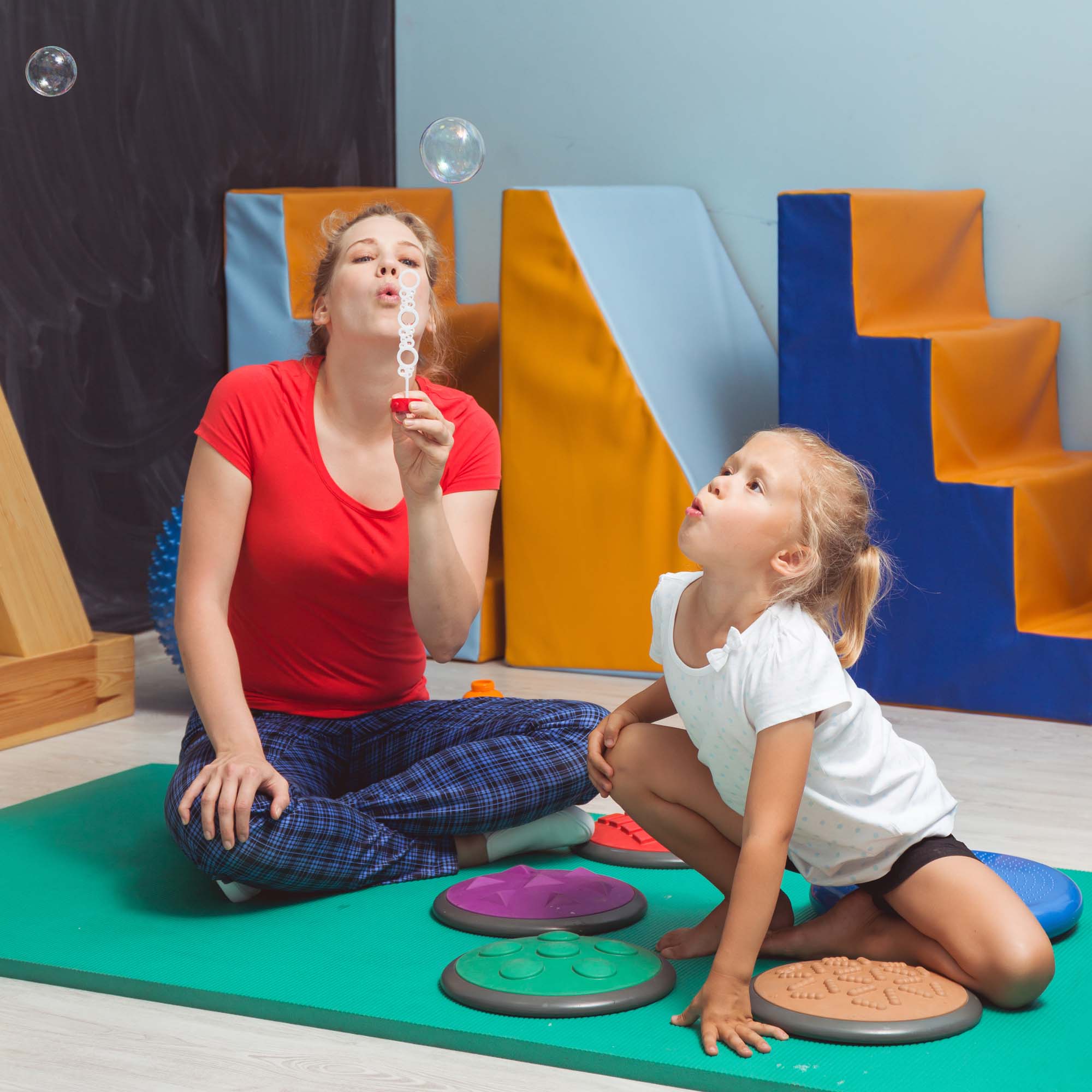 Child and therapist blowing bubbles during sensory integration therapy